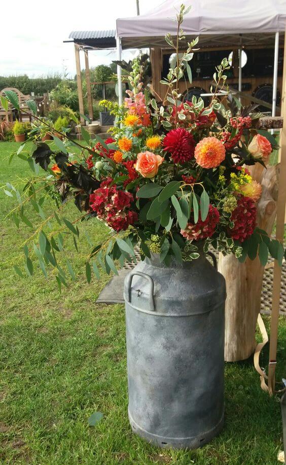 Bright autumnal milk churn flower arrangement at Bridge House Barn, Kibworth